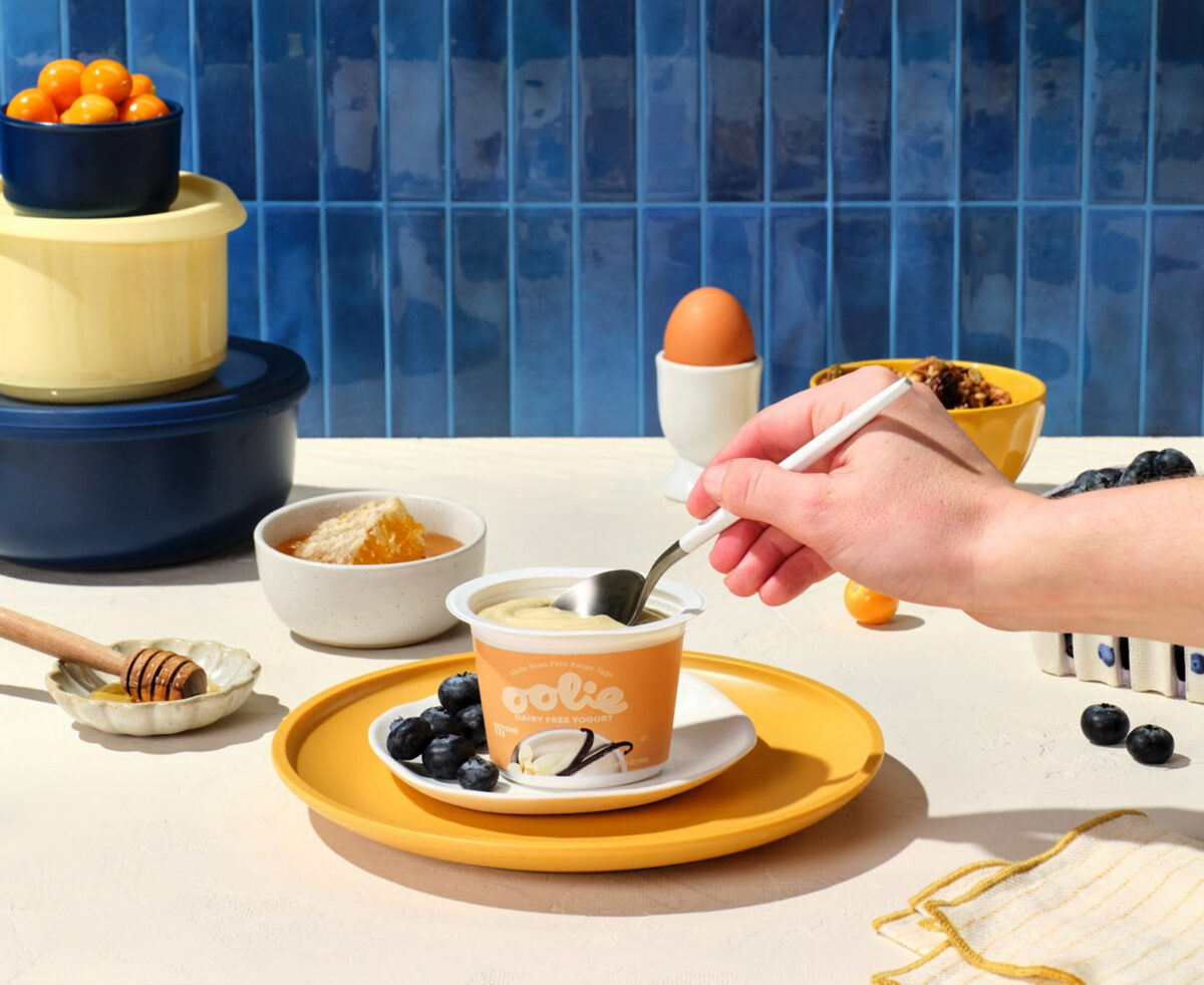 hand holding spoon dipping into a cup of Oolie yogurt