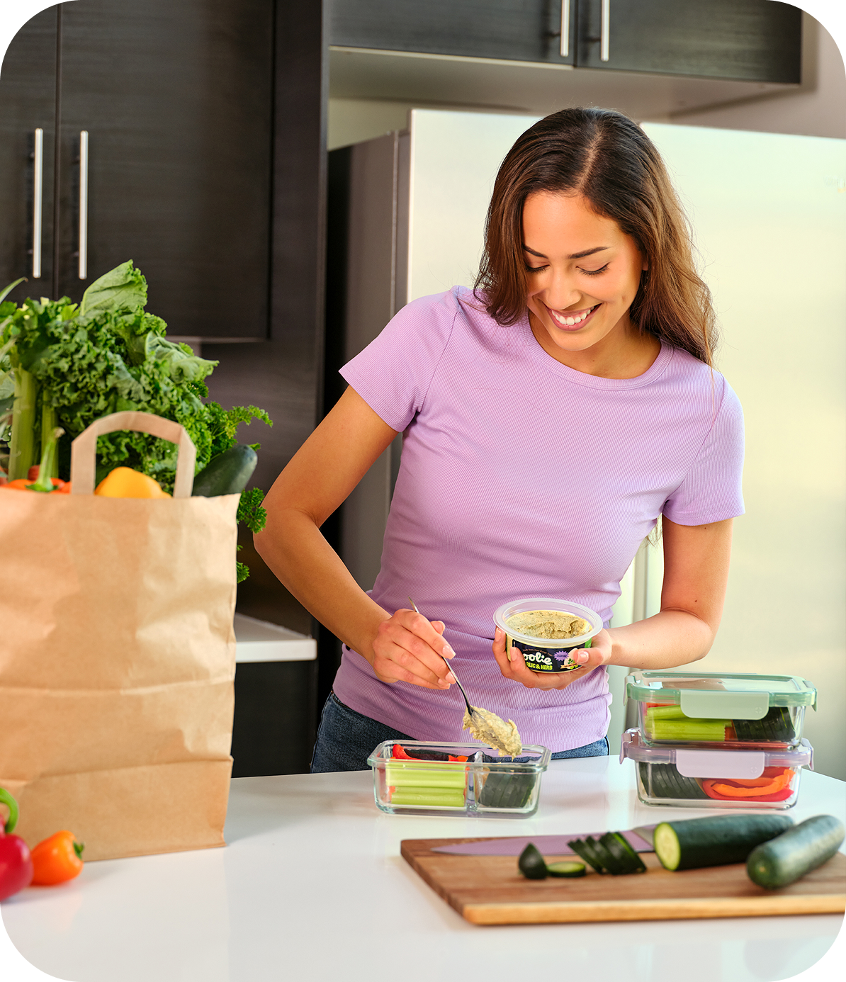 Woman spooning Oolie dip into a meal prep container with veggies